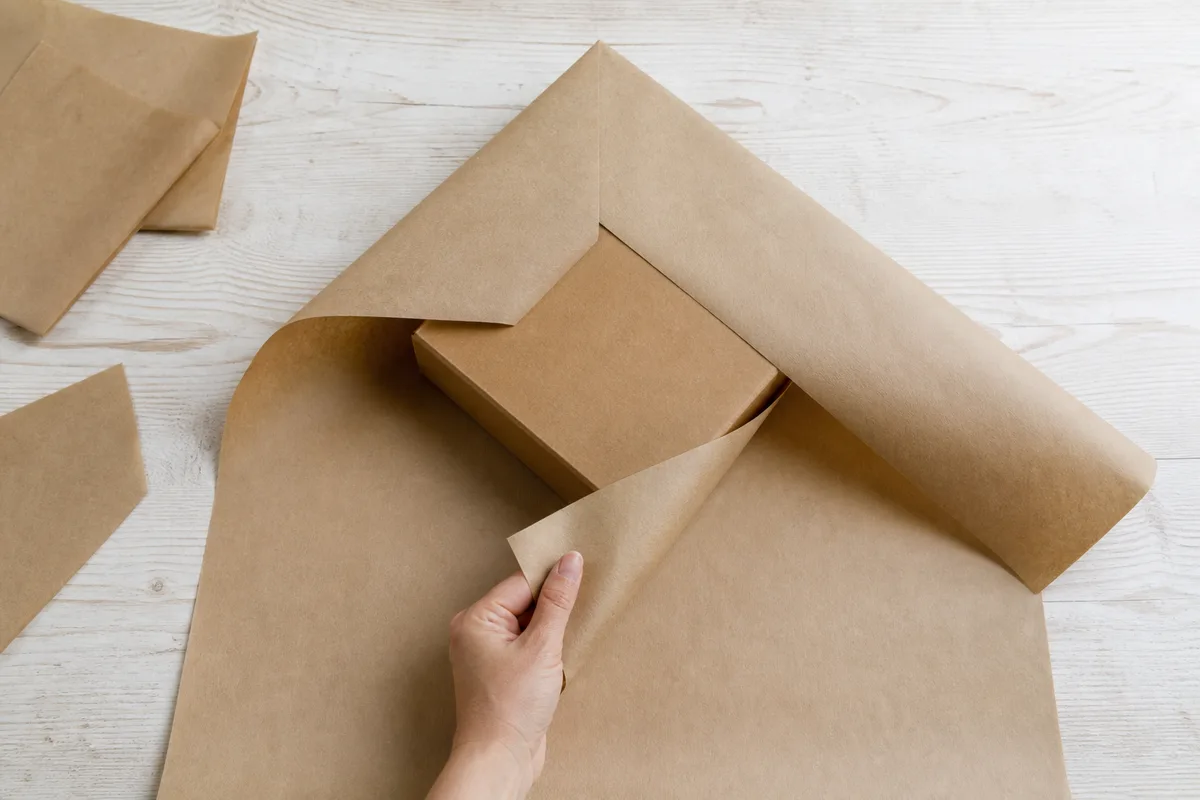 Boîte posée en biais sur une feuille de papier kraft, pointes rabattues vers le centre